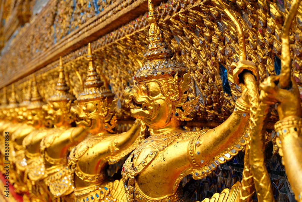 Fototapeta premium Garuda in (Wat Phra Kaew ) Temple of the Emerald Buddha Bangkok Thailand - A line of golden demons at the Grand Palace in Bangkok, Thailand