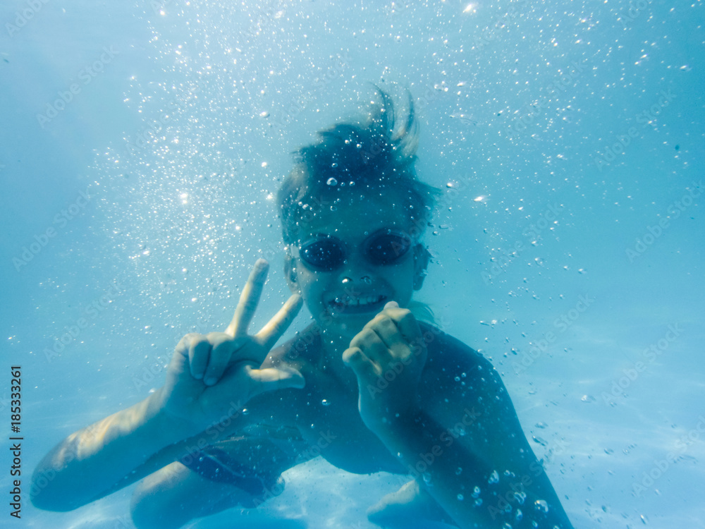 Underwater Young Boy having fun in the Swimming Pool with Goggles