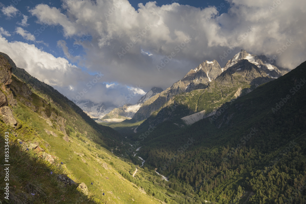 Obraz premium Summer views of the snowy mountains of the Caucasus. Formation and movement of clouds over mountains peaks.