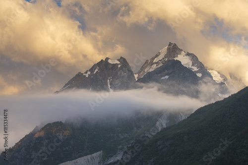 Summer views of the snowy mountains of the Caucasus. Formation and movement of clouds over mountains peaks.