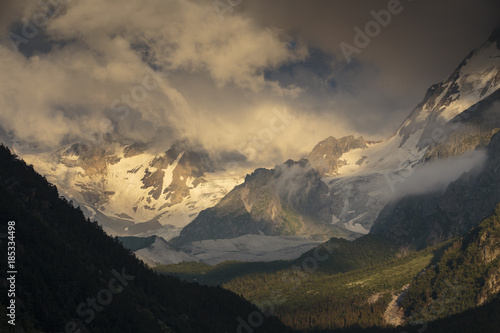 Summer views of the snowy mountains of the Caucasus. Formation and movement of clouds over mountains peaks.