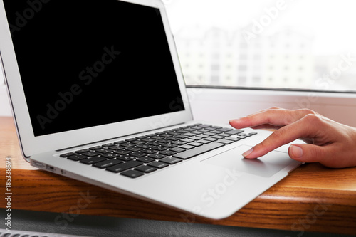 Close up of hands typing on a laptop in a coffee shop