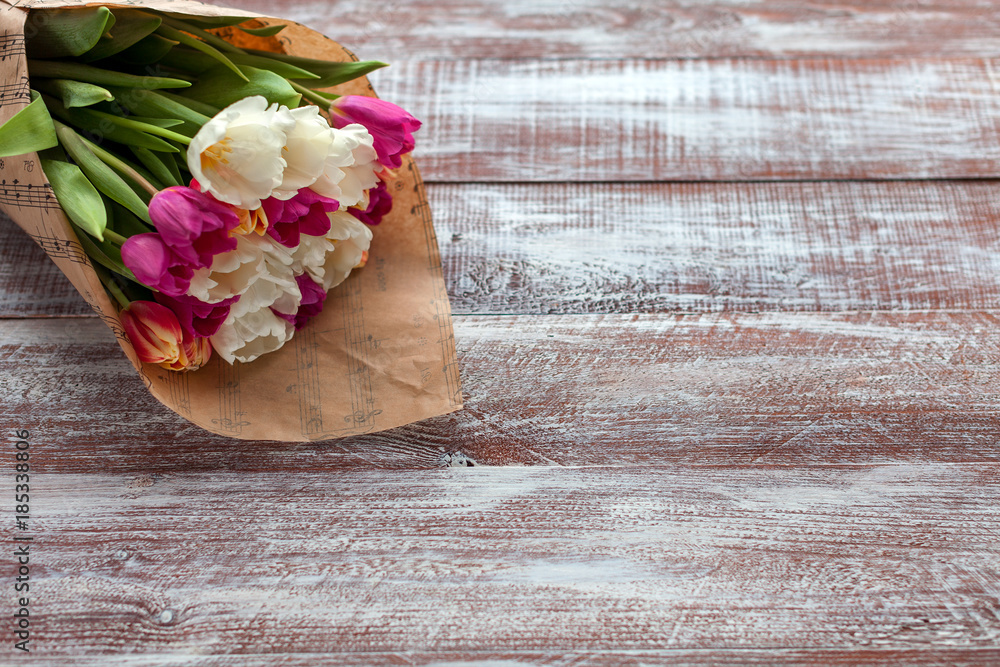 the bouquet of tulips is wrapped in a paper isolated on a wood background the bouquet of tulips is wrapped in a paper isolated on a wood background