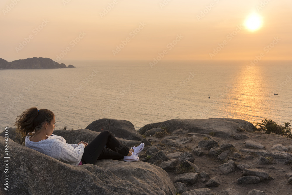 Chica viendo la una puesta de sol en frente de Islas Cies (Pontevedra, España).