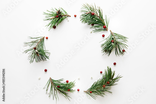 Traditional Christmas wreath made from pine branches and red berries on a white background. Flat lay, top view.