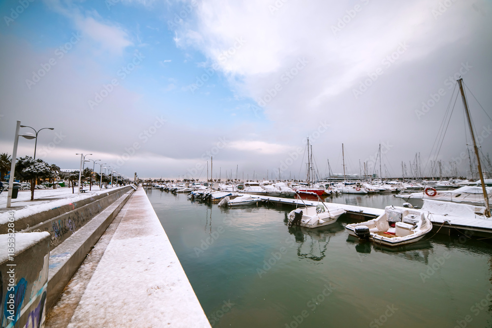 Ships and boats covered with snow in the port of the spanish town Denia