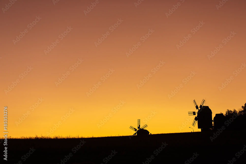 silhouette of windmills on yellow sunset sky. Copy space for text