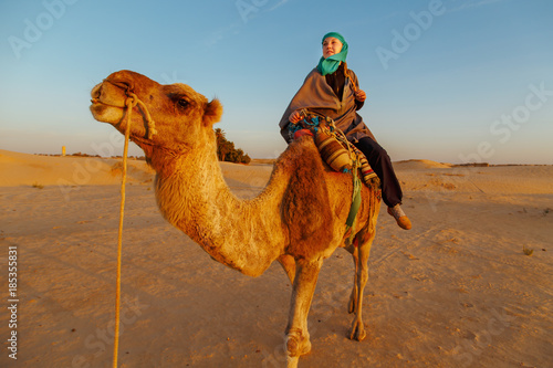 Woman  riding a camel in the Sahara desert.