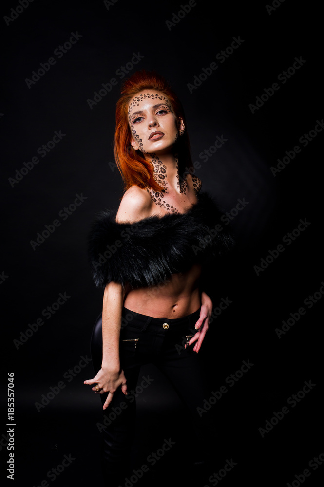 Fashion model red haired girl with originally make up like leopard predator isolated on black. Studio portrait. Fashion model red haired girl with originally make up like leopard predator isolated on black. Studio portrait.