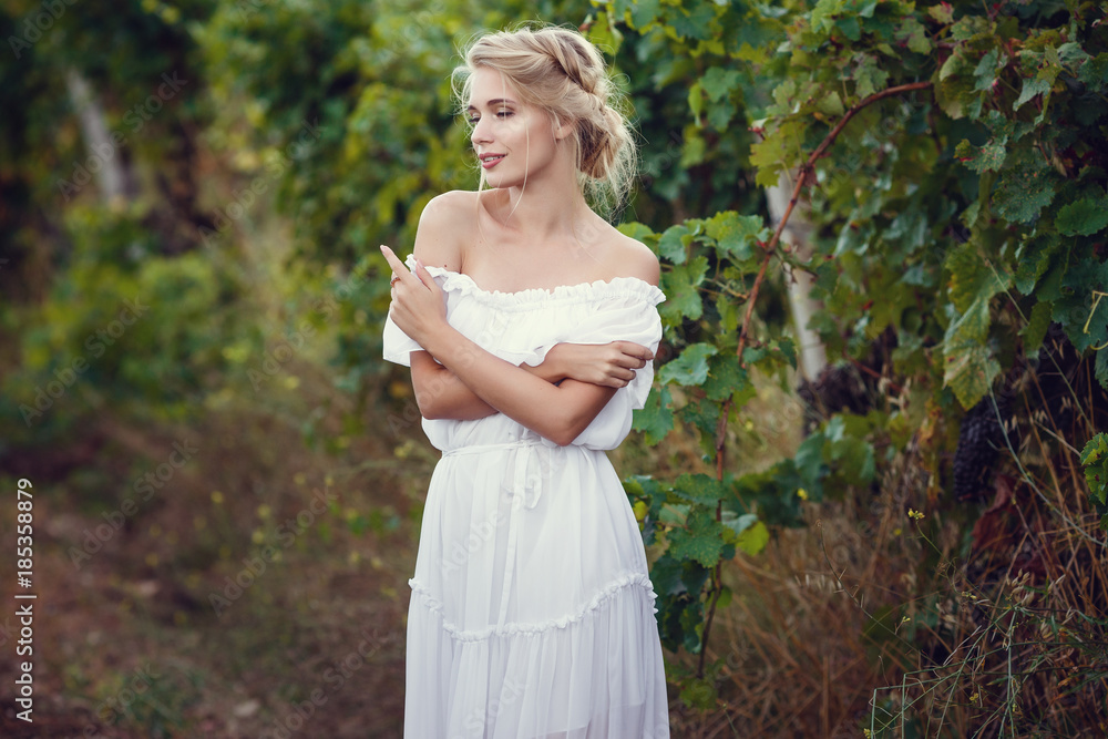 Beautiful blond girl with basket of grapes in a vineyard Beautiful blond girl with basket of grapes in a vineyard