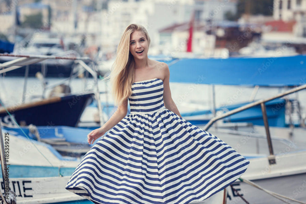 beautty fashion portrait of blonde woman stripped dress. Fashion portrait. Smiling blonde woman in fashionable look. Sea style.