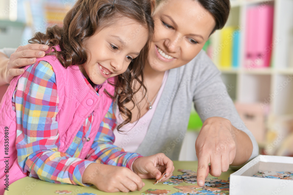 Mother with little daughter collecting puzzle Mother with little daughter collecting puzzle