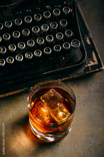 Glass of whiskey and a retro typewriter photo