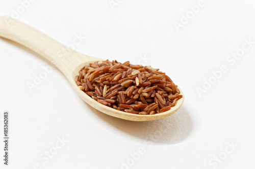 Thai Black or dark brown raw rice in a wooden spoon for a healthy diet. High fiber, vitamin, carbohydrate, minerals, and nutrition for healthy people. on the white background, isolate.