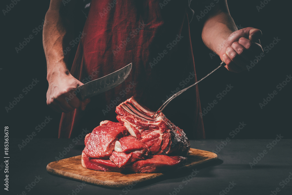 Εκτύπωση καμβά butcher with fork and knife cutting raw meat on wooden cutting board