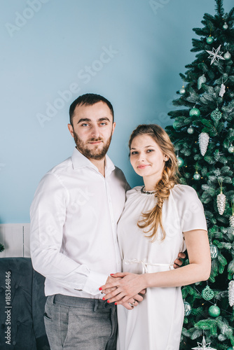 A young beautiful couple celebrating New Year next to the Christmas tree. Christmas and New Year concept