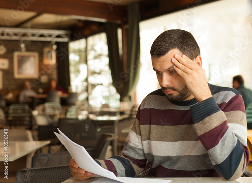 Confused man looking at papers