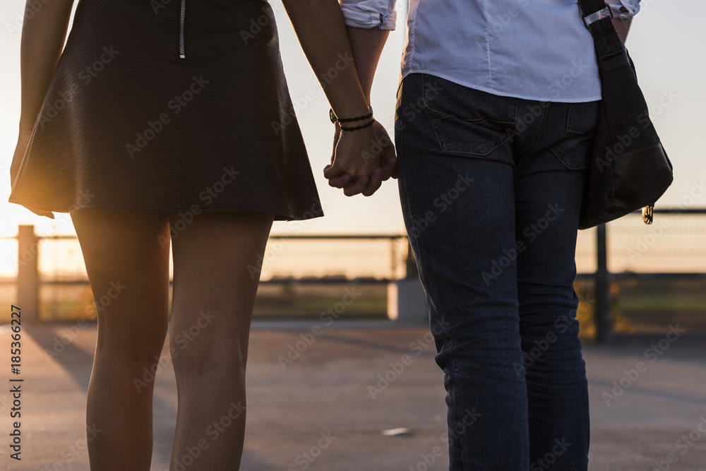 Young couple hand in hand on parking level at sunset