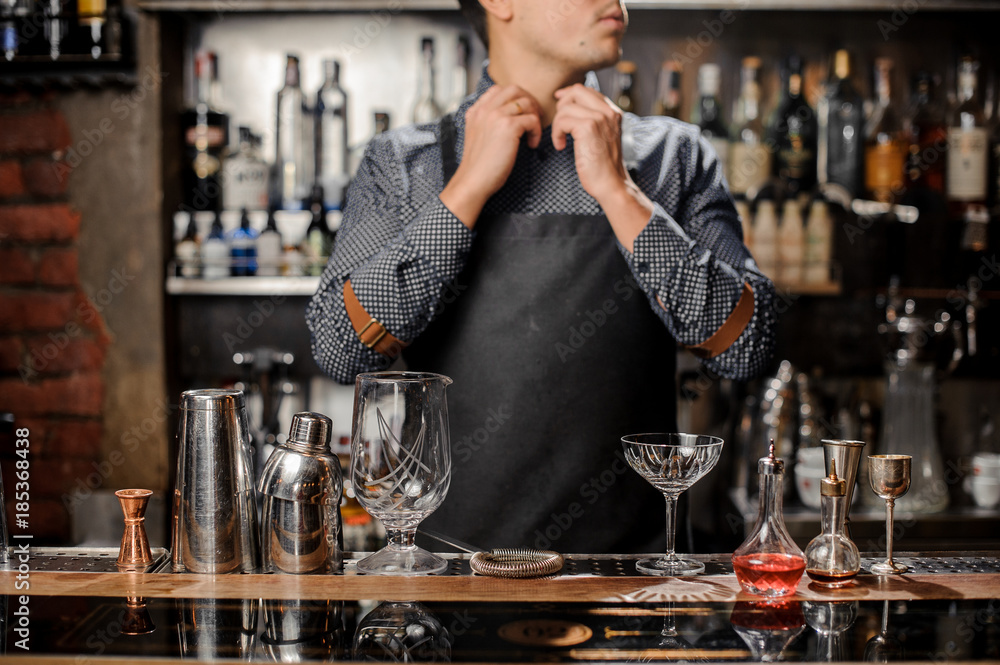 Barman standing behind the bar counter with a bar equipment