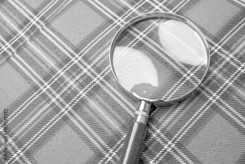 Magnifying glass on a plaid background, black and white frame photo