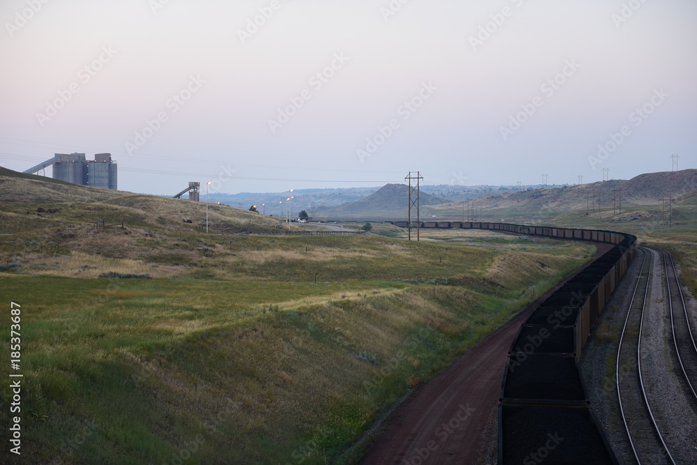 A long winding coal train passing through coal loading silos, open pit coal mining, Powder River Basin, Wyoming.