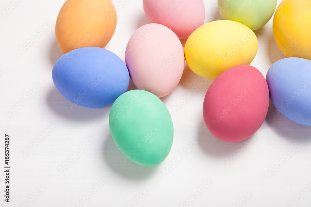 Easter composition with colored eggs on wooden white background with copy space.