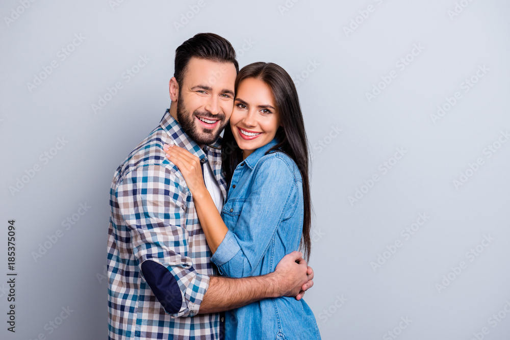 Portrait of attractive, cute, lovely, cheerful couple with beaming smiles, check to check face, looking at camera, over grey background, 14 february Portrait of attractive, cute, lovely, cheerful couple with beaming smiles, check to check face, looking at camera, over grey background, 14 february