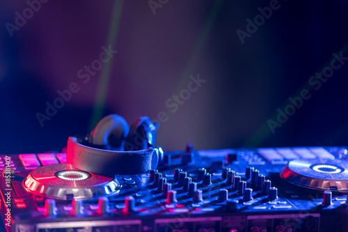 The DJ console cd mp4 deejay mixing desk Ibiza house music party in nightclub with colored disco lights. photo