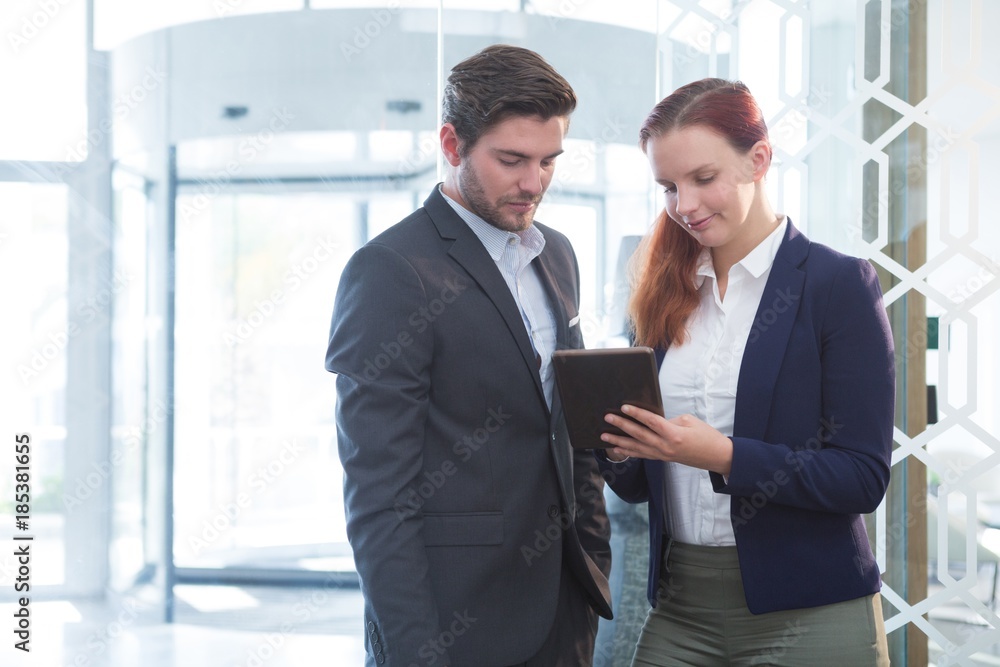 Business executives discussing over digital tablet Business executives discussing over digital tablet