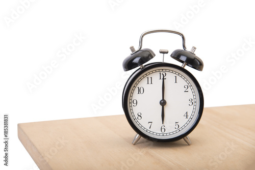 black alarm clock on wood table at morning isolated on white background.