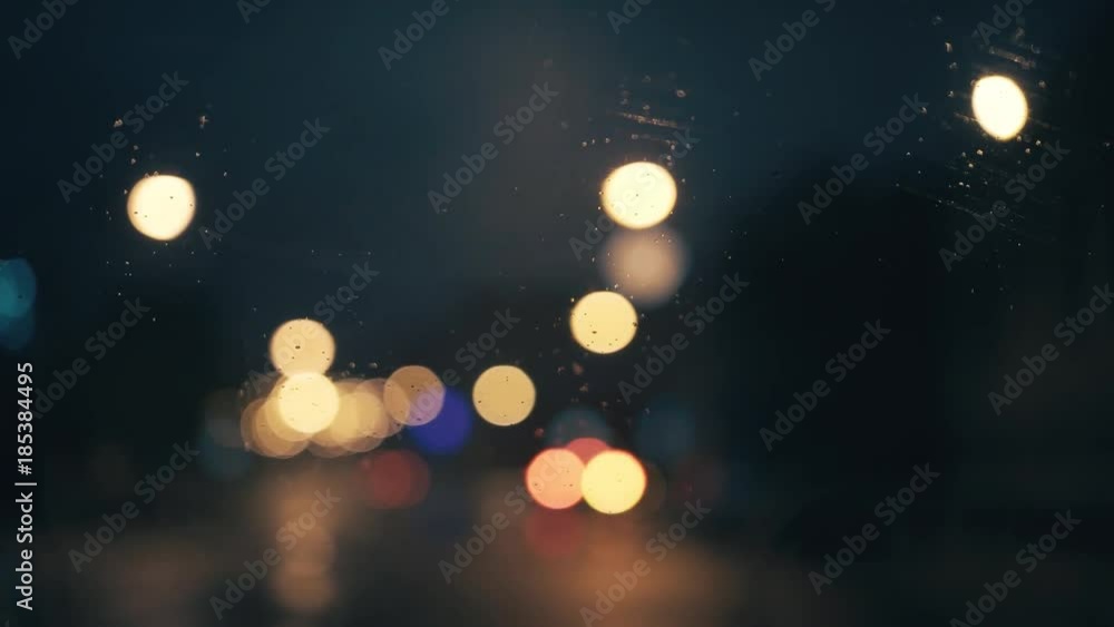 Lights the night city through the glass of the car. There is light rain Lights the night city through the glass of the car. There is light rain