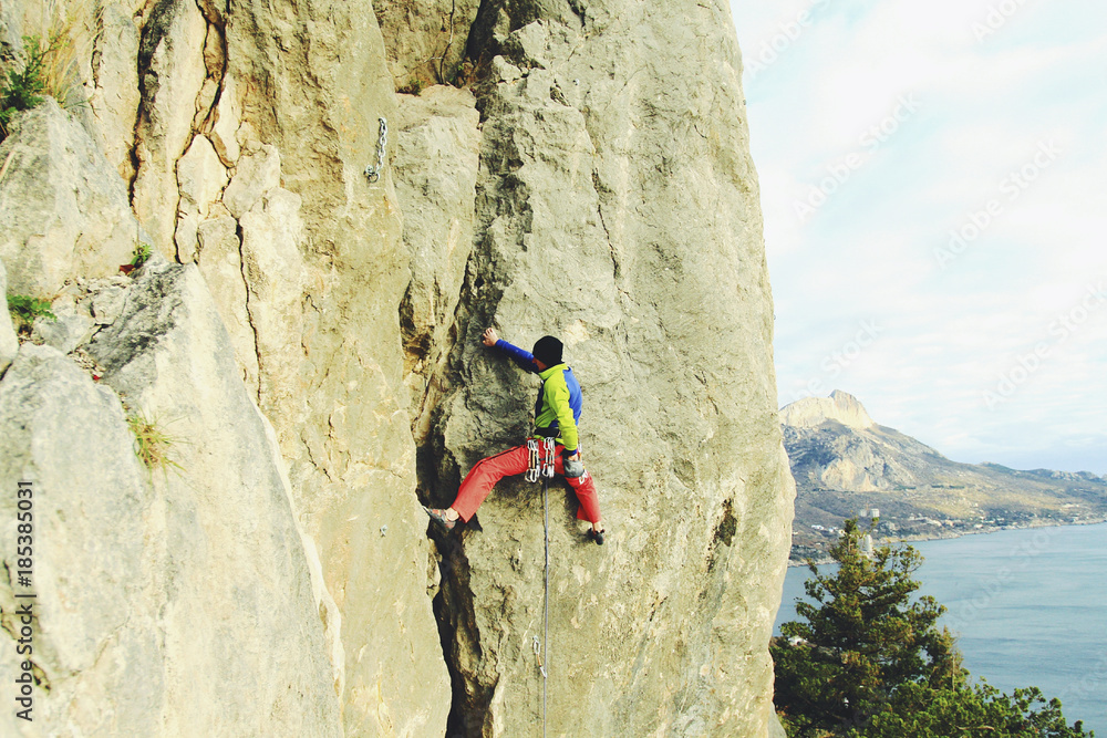 Fototapeta premium Rock climber ascending a challenging cliff. Extreme sport climbing. Freedom, risk, challenge, success.