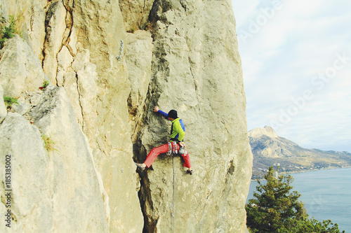 Rock climber ascending a challenging cliff. Extreme sport climbing. Freedom, risk, challenge, success.