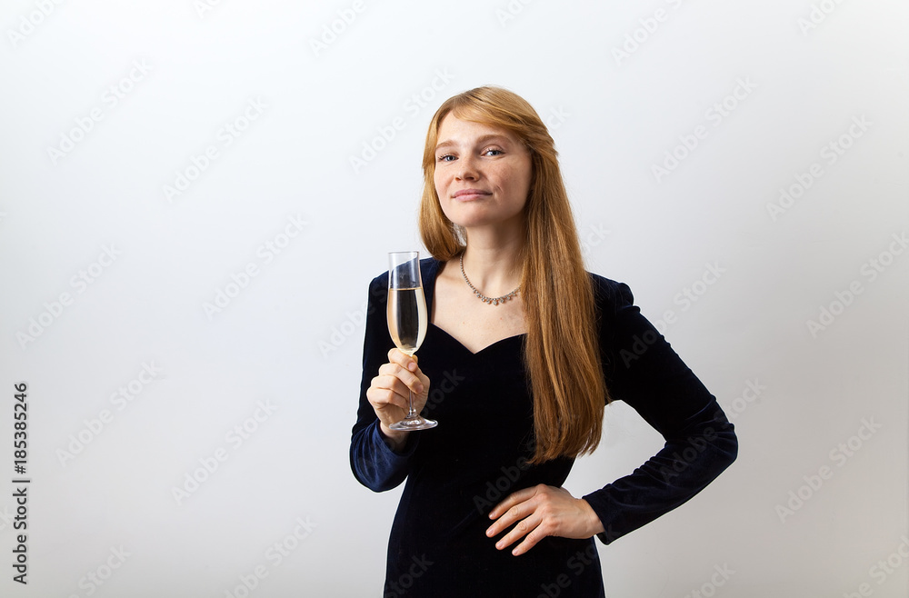Horizontal image of young elegant lady with red hair and freckles dressed in dark velvet holding a glass of champagne and looking at the camera with a challenge. White background. Horizontal image of young elegant lady with red hair and freckles dressed in dark velvet holding a glass of champagne and looking at the camera with a challenge. White background.