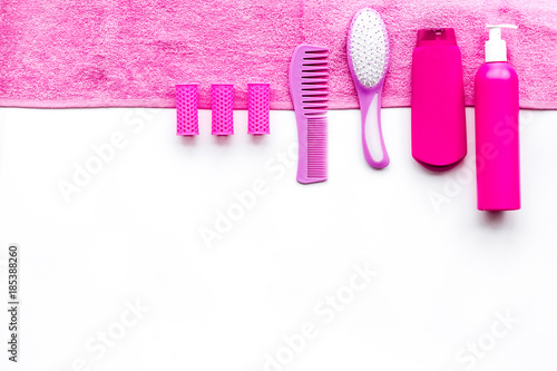 Basic hair care in bathroom. Comb, shampoo, spray, curlers, towel on white background top view copyspace