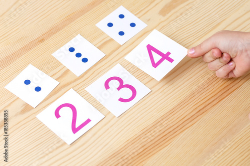 The child spreads cards with numbers to cards with dots. The study of numbers and mathematics
