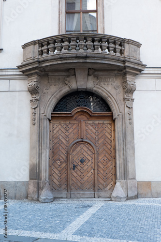 Elaborate doorway in Prague, Czech Republic. Herringbone pattern in wood on a door with a carved stone surround, iron details on fan light above the door, stone balcony and carved balustrade. photo