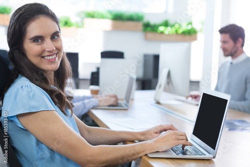 Smiling female executive using her laptop in the office