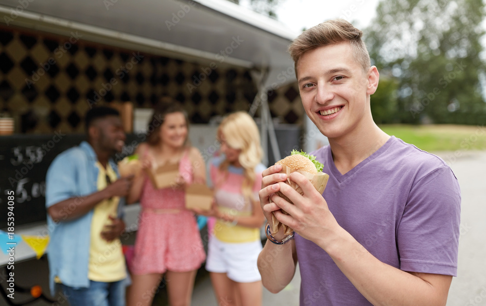 happy man with hamburger and friends at food truck
