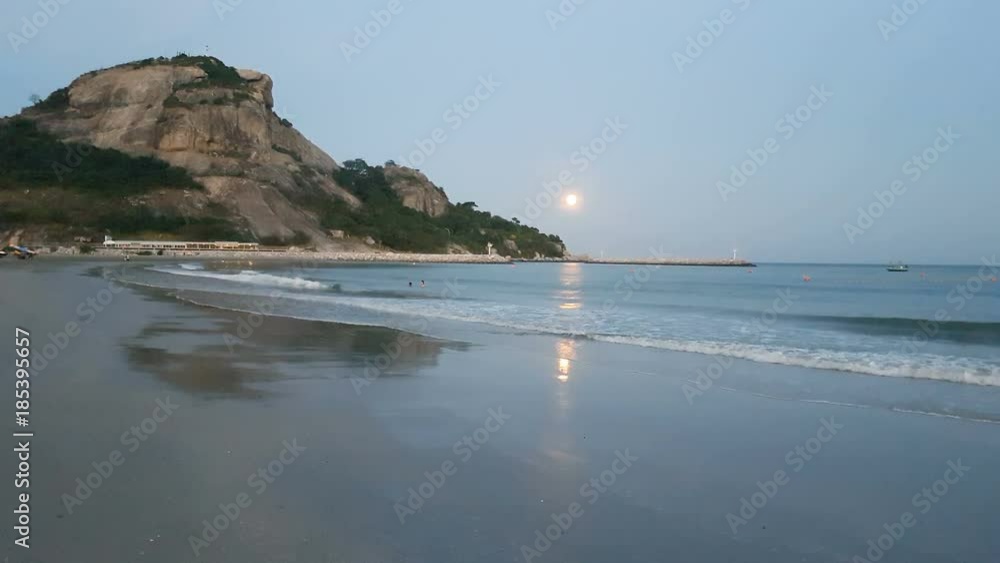 landscape view of low full moon over the sea with mountain and sea wave or tide come to beach when dusk in the evening. landscape view of low full moon over the sea with mountain and sea wave or tide come to beach when dusk in the evening.
