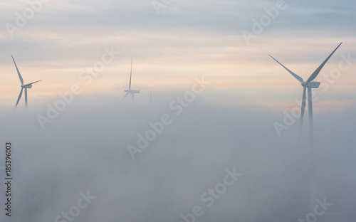 Parque eólico al amanecer en medio de la niebla