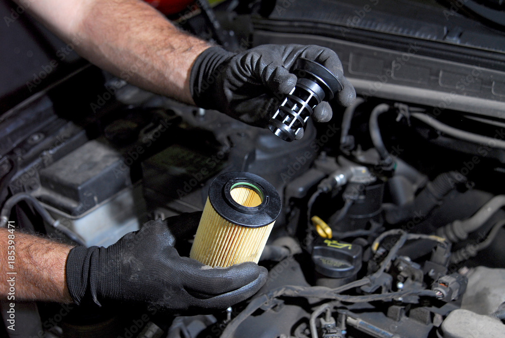 mechanic in the hand, remove car oil filter - obrazy, fototapety, plakaty 