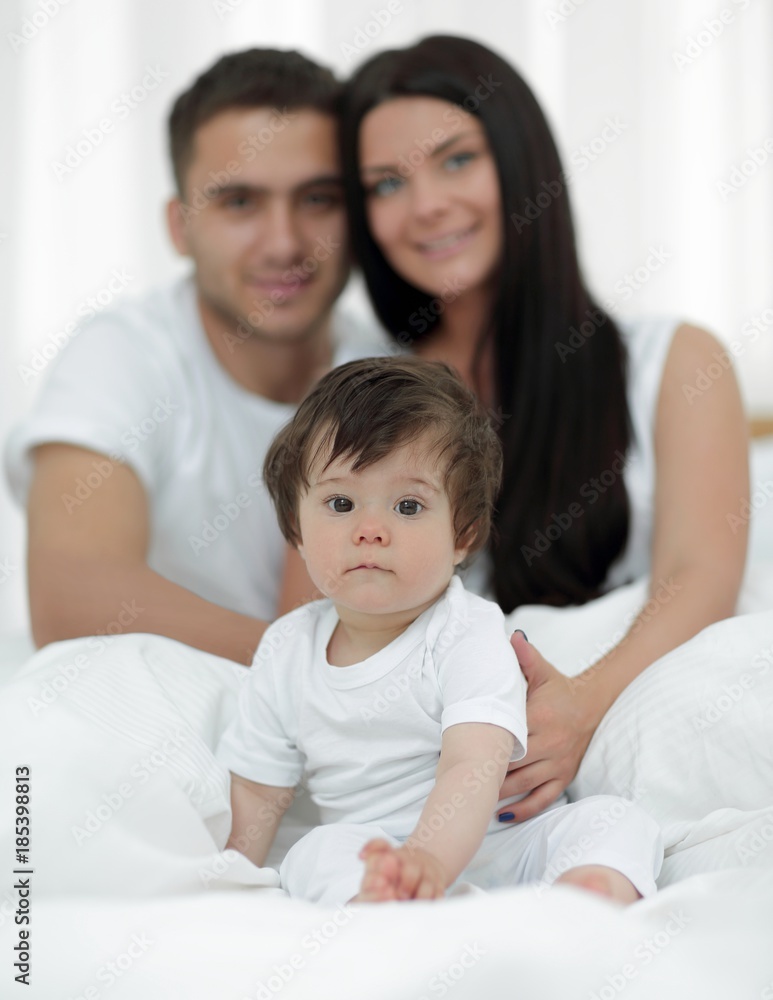 Happy couple and son sitting in bed