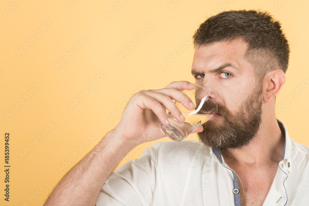 Man with long beard hold water glass on yellow background. Man with long beard hold water glass on yellow background.