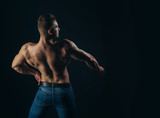 Athlete man with bare torso in blue jeans, back view