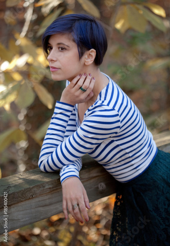 Young Woman With Pixie Haircut Leaning Against Wooden Railing Outside