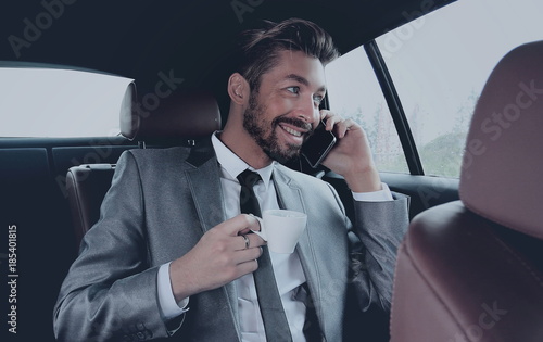 Young businessman having a coffee in his car