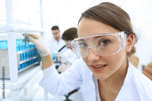 Young woman scientist in protective glasses holding test tubes