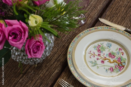 Fork and butter knife with plate arranged on wooden table © wavebreak3