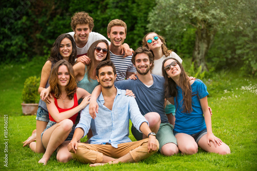 Group of young people sitting in the grass, posing for a photo © jackfrog